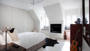 Une chambre à coucher avec un lit, un téléviseur fixé au mur, une guitare et un tapis en peau de vache.