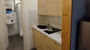 Une cuisine compacte avec des meubles en bois, un plan de travail noir et une cuisinière intégrée.
