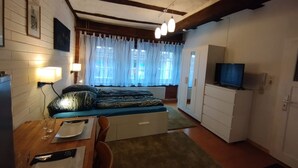Une chambre confortable avec un lit, un bureau doté d’une lampe, une télévision et une armoire.