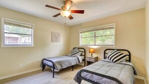 A bedroom with two single beds, a ceiling fan, and two windows. - The Temple Retreat (Temple)