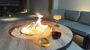 A round outdoor fire pit with ice, two glasses of wine, and a candle on a wooden table. - Spacious & Stocked: 2Kings+Hot Tub+Fire Pit+Family Fun (Albuquerque)