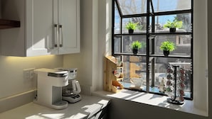 A kitchen with a coffee maker, a window with potted plants, and a coffee mug rack. - Spacious & Stocked: 2Kings+Hot Tub+Fire Pit+Family Fun (Albuquerque)