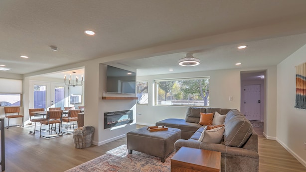 A spacious living room with a large sectional sofa, a dining area with a table and chairs, and a fireplace. - Spacious & Stocked: 2Kings+Hot Tub+Fire Pit+Family Fun (Albuquerque)