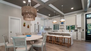 A modern kitchen with white cabinetry, a round dining table, and a central island with stools. - 4 Bed/3.5 Bath! Pool! Amenity access included! Golf Course Views! (Seabrook Island)