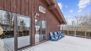 Un bâtiment en bois doté de grandes portes et fenêtres en verre, d’une terrasse couverte avec des chaises bleues, et d’un sol recouvert de neige.