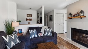 Un salon avec un canapé bleu foncé, une table basse en bois et une cheminée.