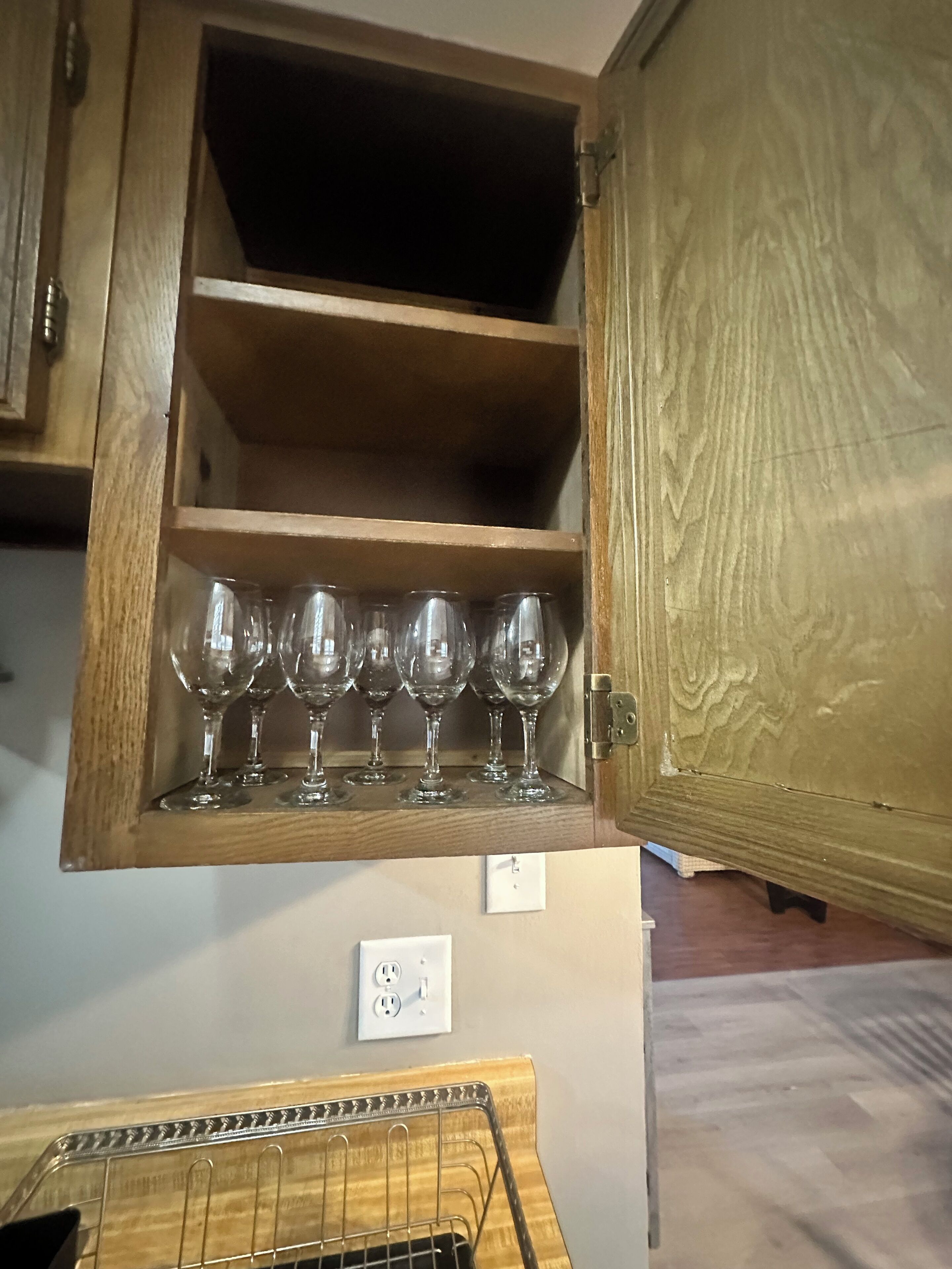 Un meuble en bois muni d’une étagère où sont rangés plusieurs verres à vin.
