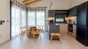 A modern kitchen with a dining area, featuring a wooden ceiling, large windows, and a central island. - Elegant house with Private Pool (Schinias)