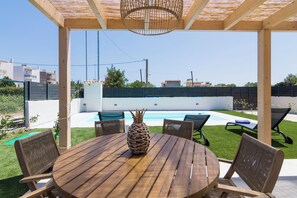 Relax in an outdoor seating area with a round table and four chairs, overlooking the pool and serene surroundings.