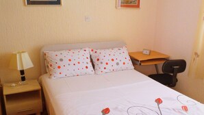 Une chambre d’hôtel avec un lit, une table de chevet avec une lampe, un bureau et une chaise.