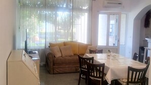 A dining area with a table set for four, a sofa, and a TV in the background. - Two Bedroom Apartment with Terrace (Novi Vinodolski)