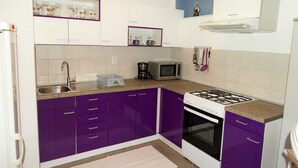 A kitchen with purple cabinets, a white stove, a microwave, and a sink. - Two Bedroom Apartment with Terrace (Novi Vinodolski)