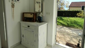 Ein weißes Schränkchen mit einem Vintage-Radio, einem Spiegel und einer kleinen Statue.