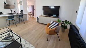 A modern living room with a sofa, a TV, and a dining area with chairs and a table. - Two Bedroom Apartment with Balcony and Sea View (Crikvenica)