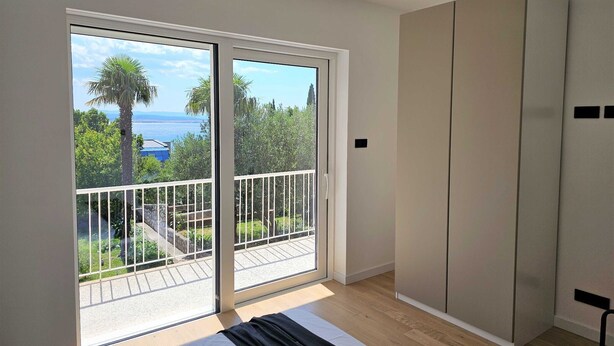 A bedroom with a large sliding glass door leading to a balcony, a bed, and a wardrobe. - Classic Two Bedroom Apartment with Balcony and Sea View (Crikvenica)