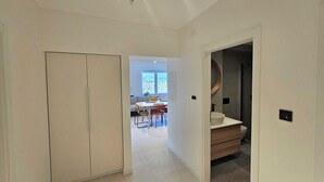 A modern interior with a hallway leading to a dining area and a bathroom. - Classic Two Bedroom Apartment with Balcony and Sea View (Crikvenica)