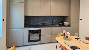 A modern kitchen with grey cabinetry, a black marble backsplash, and a built-in oven. - Classic Two Bedroom Apartment with Balcony and Sea View (Crikvenica)