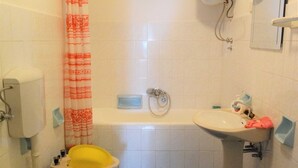 Kylpyhuone, jossa on kylpyamme, pesuallas, wc ja suihkuverho.