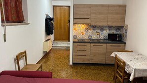 A compact kitchen with wooden cabinets, a tiled backsplash, and a microwave. - Holiday home Alpine Serenity  (Aosta)