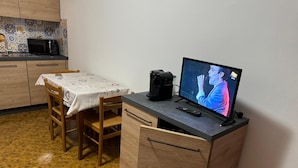 A compact kitchen with a microwave, a coffee maker, and a TV on a wooden cabinet. - Holiday home Alpine Serenity  (Aosta)