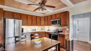 A modern kitchen with wooden cabinets, stainless steel appliances, and a dining area with a wooden table and chairs.