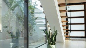 Ein modernes Interieur mit einer Glaswand, Blumentöpfen und einer Treppe.