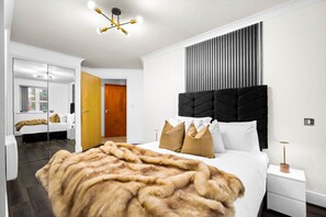 Un dormitorio moderno con una cama grande, un espejo, un armario y una lámpara de techo original.