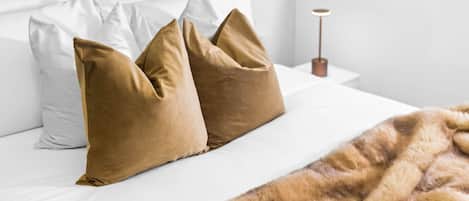 A bed with white and brown pillows, a fur throw, and a bedside lamp.