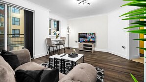 Uma sala de estar moderna com sofá, mesa de centro, televisão e área de jantar com cadeiras e mesa.