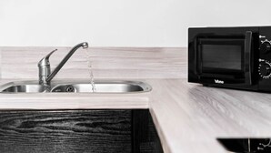 Uma cozinha com uma pia de aço inoxidável e um micro-ondas preto.