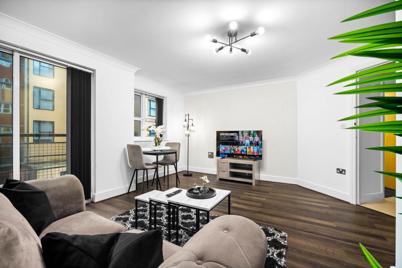 Una sala de estar moderna con un sofá, una mesa de centro, un televisor y un comedor con sillas y una mesa.