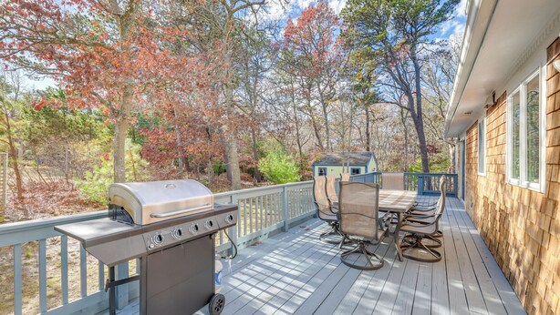 A covered deck with a grill, outdoor furniture, and a view of trees. - Great for Families! Brewster Home 6 Mi to Beach (Brewster)