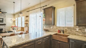 Una cocina moderna con encimeras de granito, muebles oscuros y una isla grande.