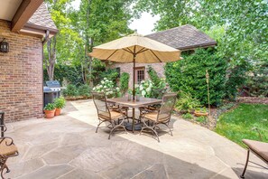 A patio with a stone table and chairs, an umbrella, and a brick building. - Walk to DU, Dining & Parks: Spacious Denver Home! (Denver)