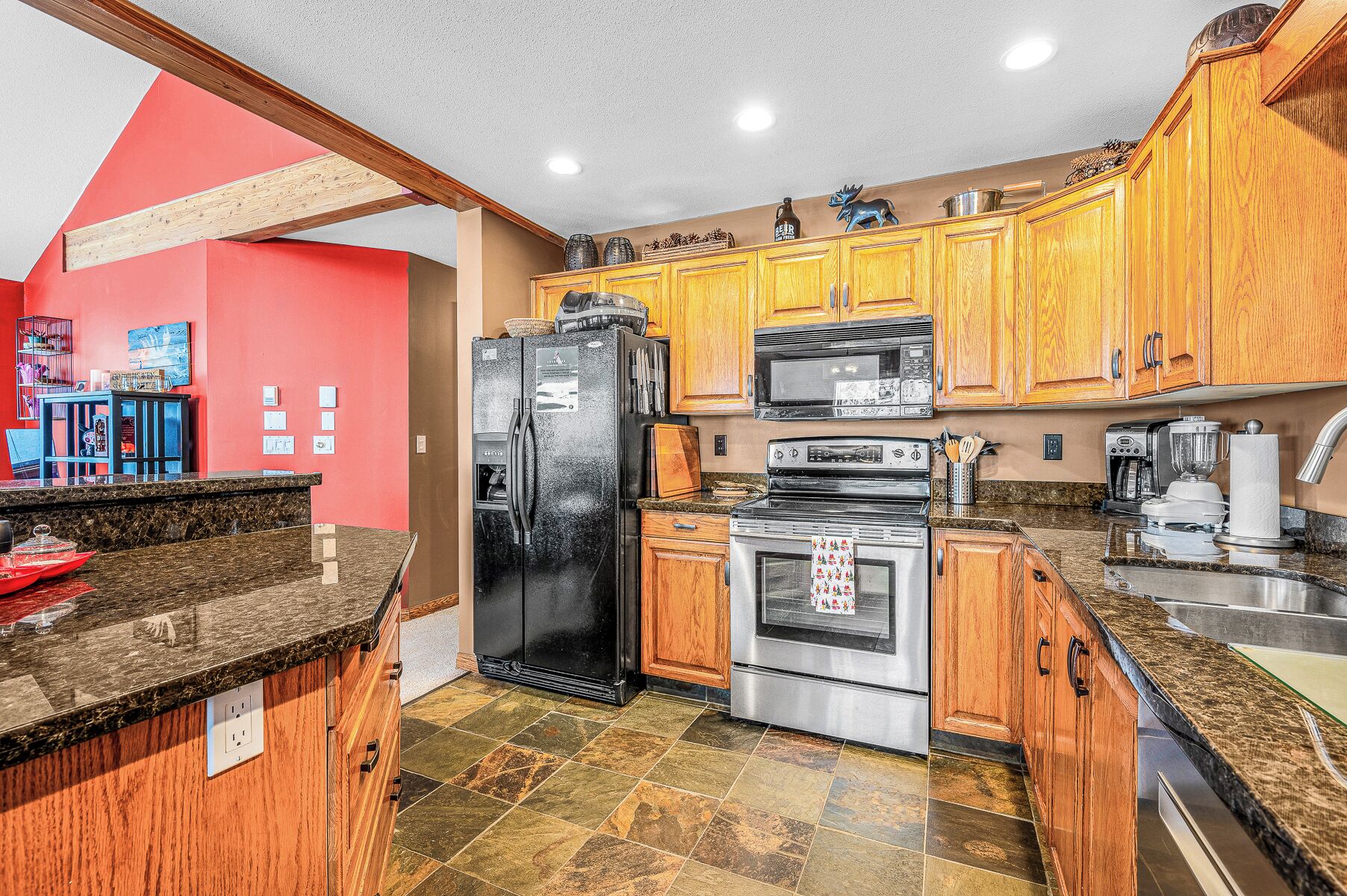 A kitchen with wooden cabinets, a black refrigerator, a stove, and a microwave.