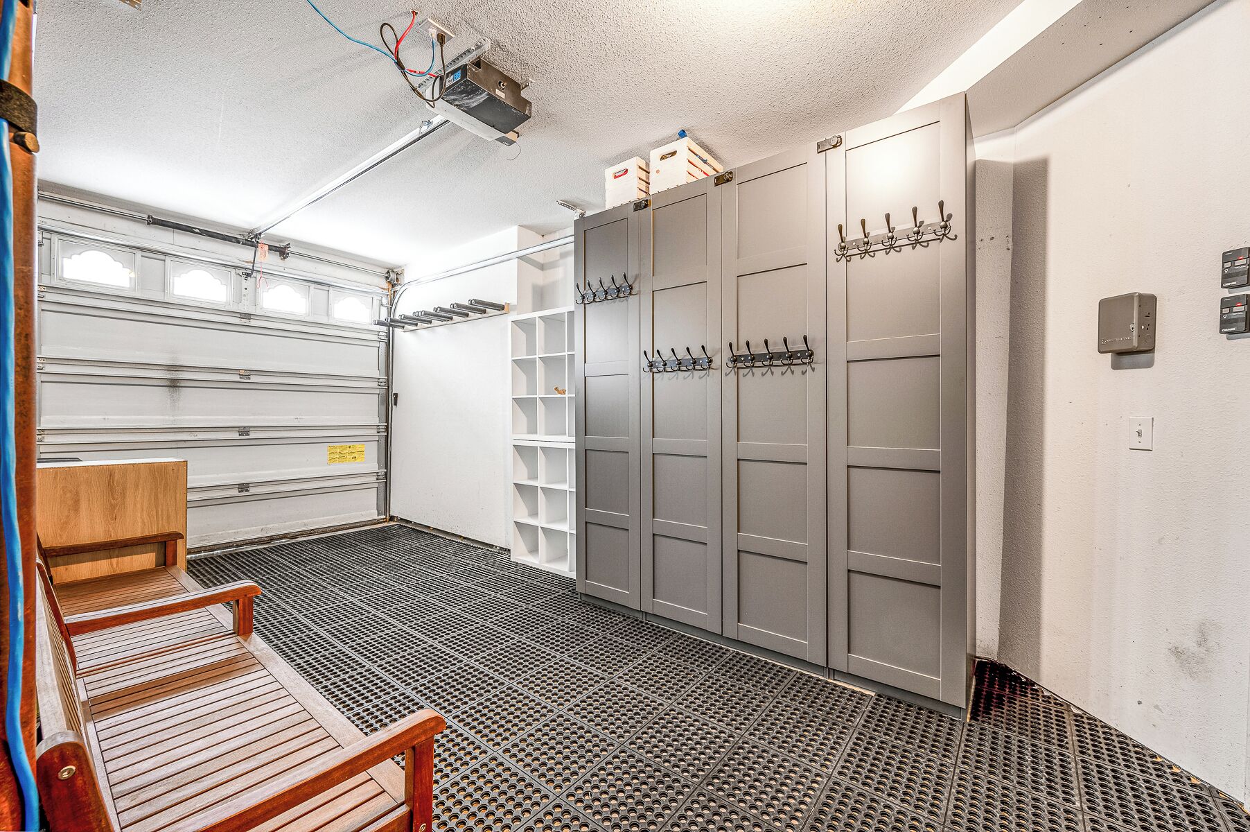 A garage with a wooden bench, metal grates, and grey lockers.