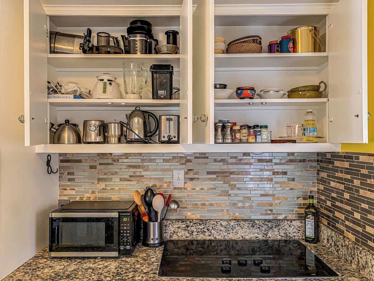 A kitchen with a microwave, stove, and various kitchen utensils.