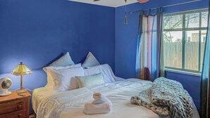 Ein Schlafzimmer mit einem Bett, einem Nachttisch, einer Lampe und einem Deckenventilator.