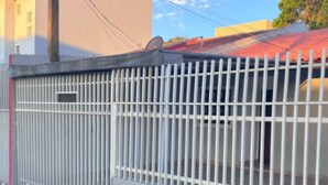 A gated property with a metal fence, a concrete pathway, and green grass in front. - Cozy House in Curitiba (São Lourenço Curitiba)