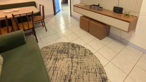 A modern living room with a dining area, a flat-screen TV mounted on a wall, a sofa, and a coffee table. - Cozy House in Curitiba (São Lourenço Curitiba)