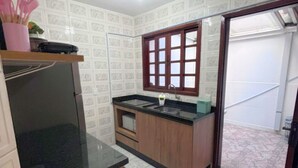 A compact kitchen with a black countertop, wooden cabinets, and a window with a grid pattern. - Cozy House in Curitiba (São Lourenço Curitiba)