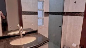 A bathroom with a granite countertop sink, a mirror, a glass shower enclosure, and a toilet. - Cozy House in Curitiba (São Lourenço Curitiba)