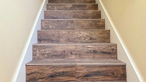 Una scala in legno con ringhiera bianca e parete beige.
