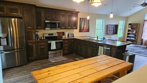 A modern kitchen with dark wood cabinets, stainless steel appliances, and a wooden dining table.