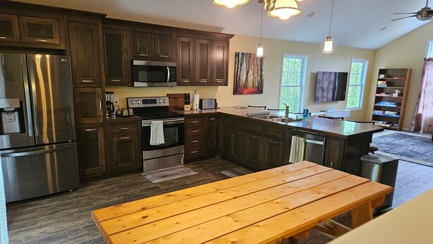 Una cucina moderna con mobili in legno scuro, elettrodomestici in acciaio inossidabile e un tavolo da pranzo in legno.