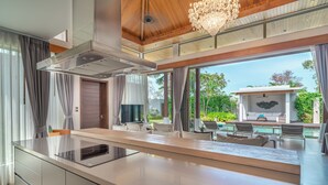 Una cocina moderna con una isla central, ventanas amplias y vistas a un área de estar exterior.