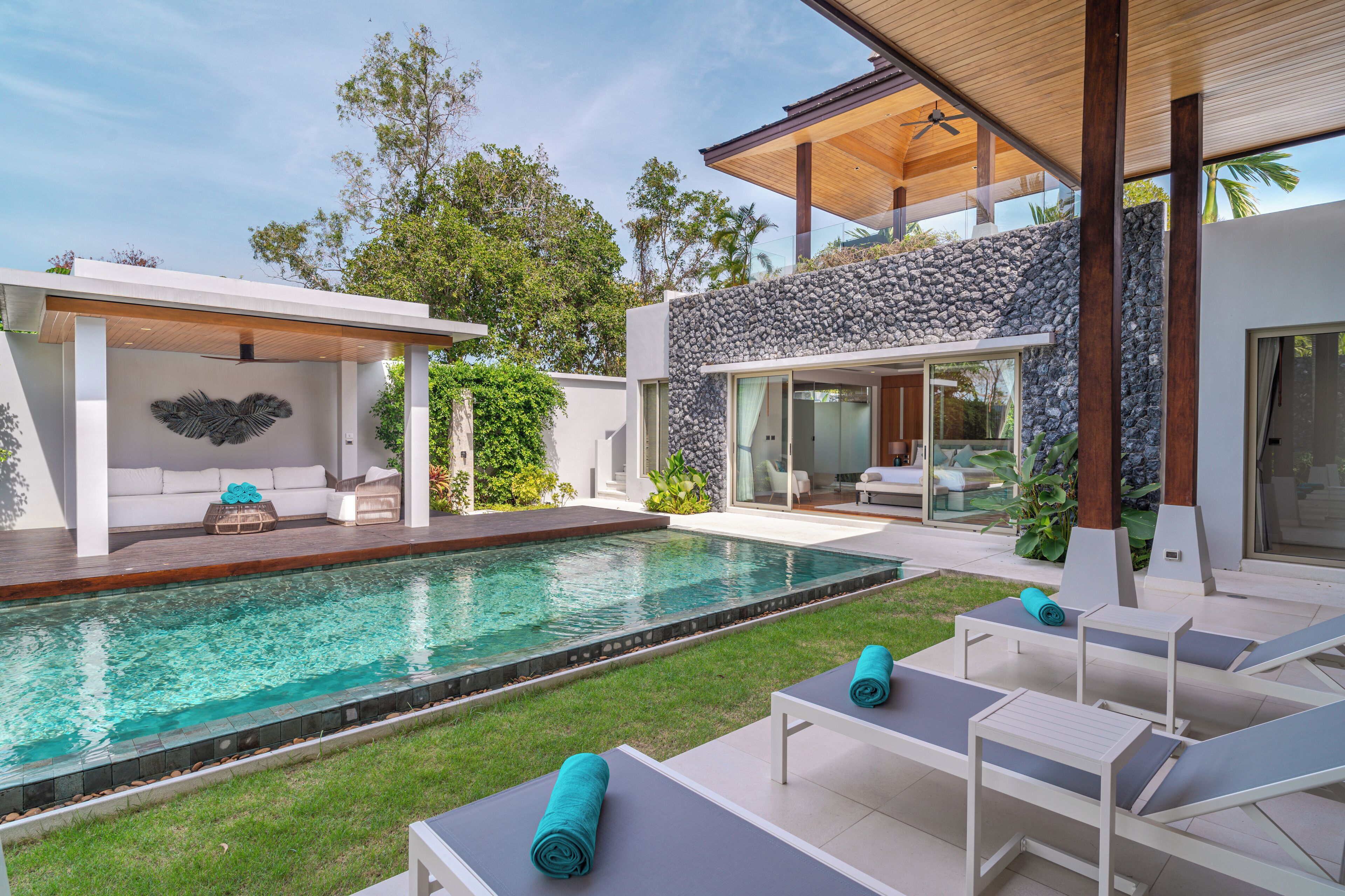 A modern outdoor pool area with lounge chairs and a covered seating area.