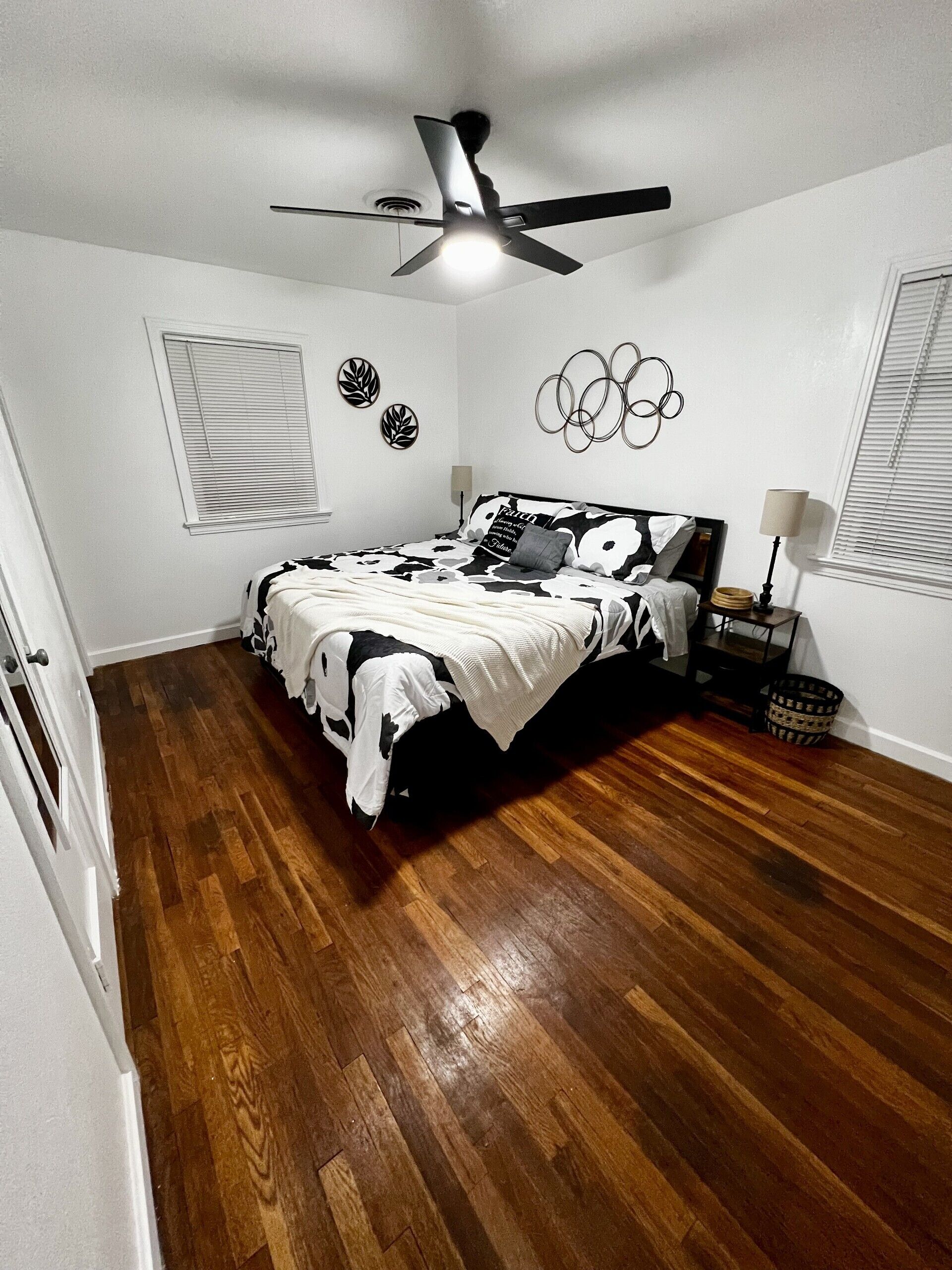 Un dormitorio con una cama, ventilador de techo, ventana con persianas y pared con adornos circulares.