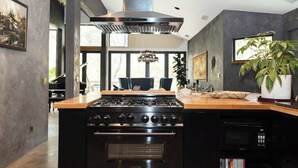 A kitchen with a large stove, oven, and microwave. There is a wooden countertop and a potted plant. - River Magic -Riverfront Luxury (Three Rivers)