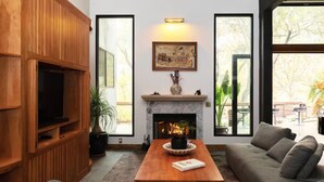 A living room with a fireplace, a television, and a sofa. - River Magic -Riverfront Luxury (Three Rivers)
